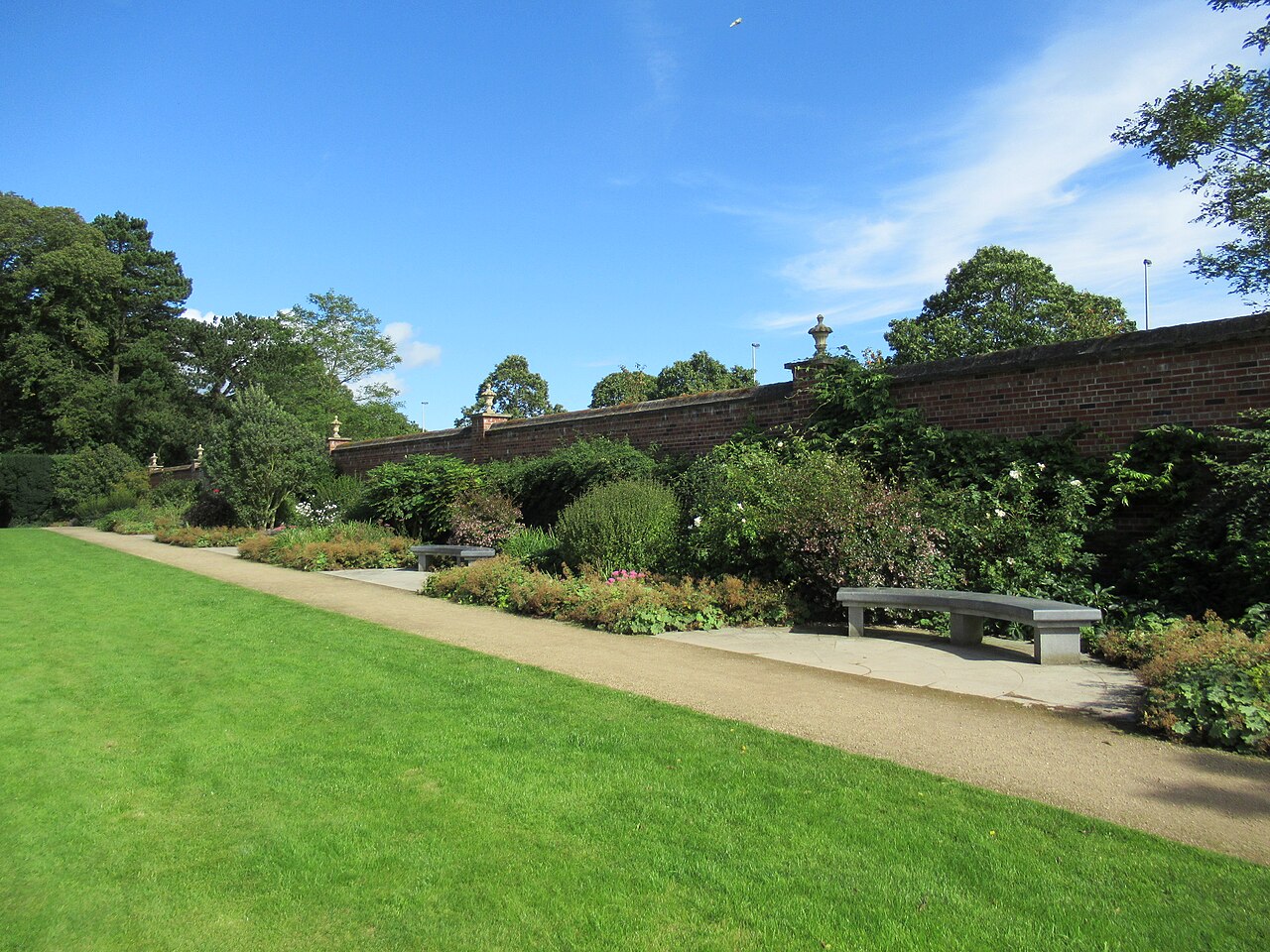 Lawn, path and planted terrace beside a brick wall at Antrim Castle Gardens