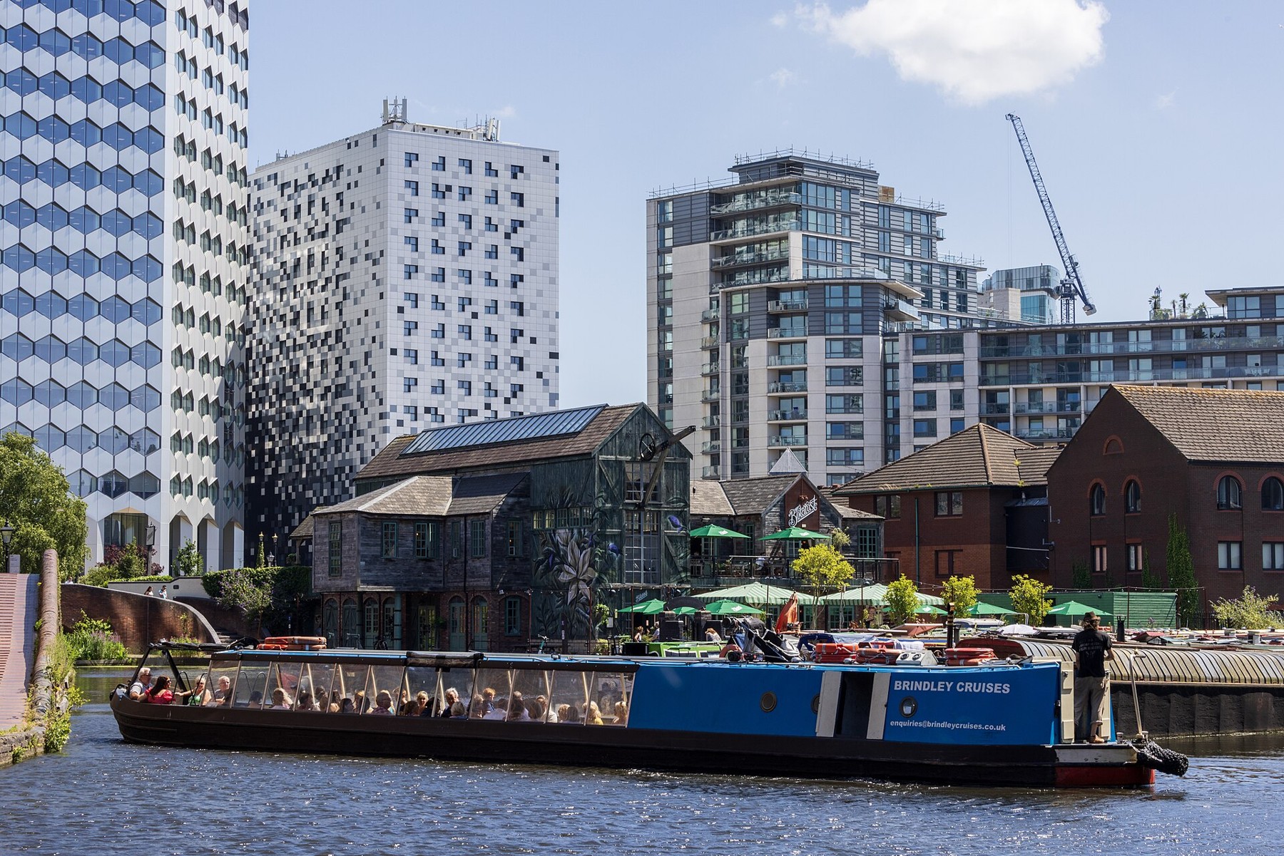 A narrowboat crossing Gas Street Basin with waterside buildings behind