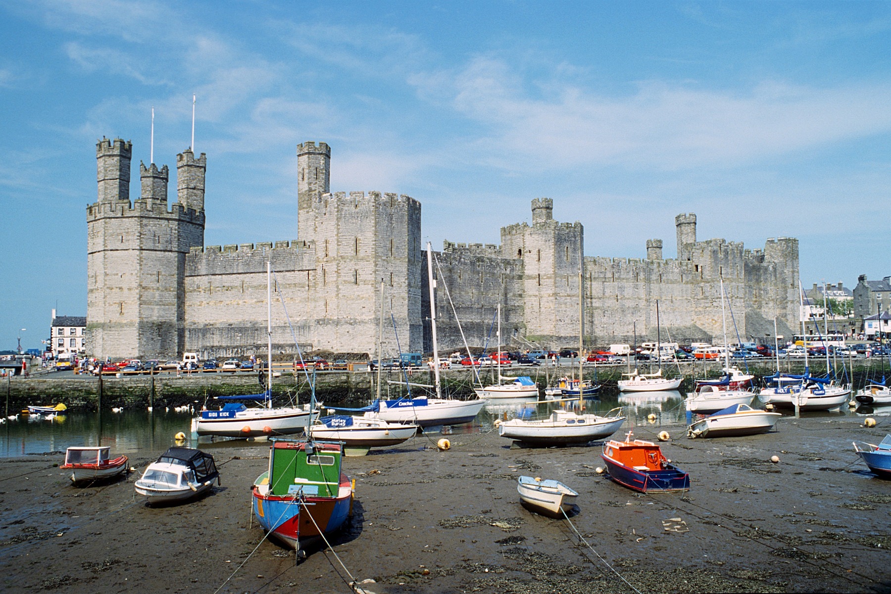 Caernarfon Castle seen across boats in the harbour at low tide