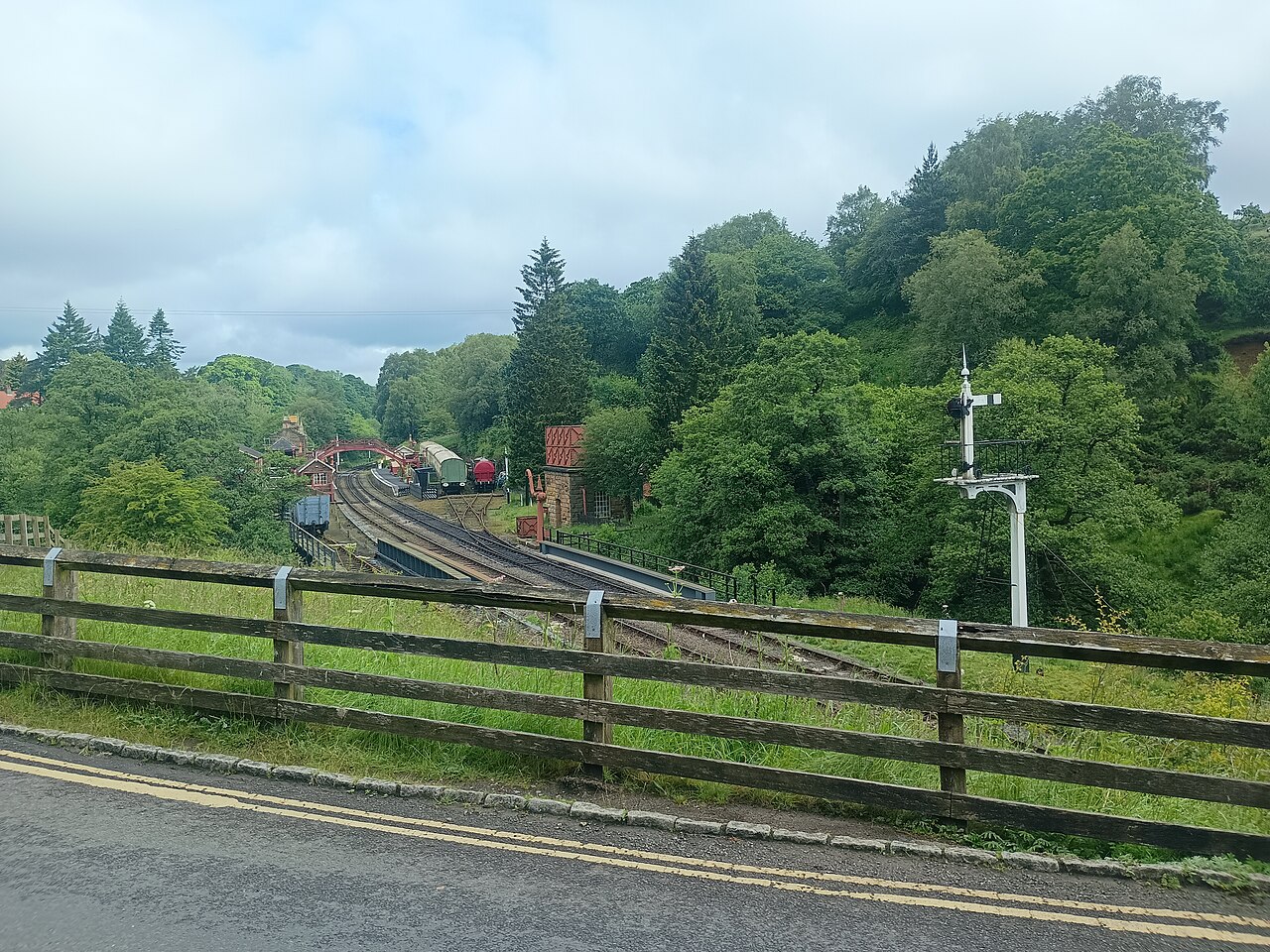 Heritage railway tracks and station buildings below trees in Goathland
