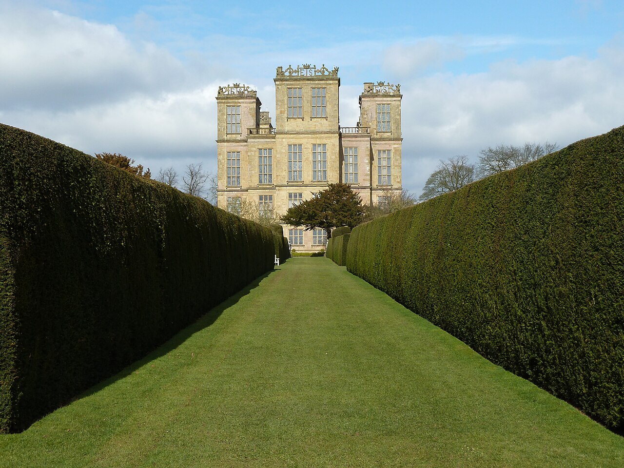 Hardwick Hall seen along a formal hedge-lined path