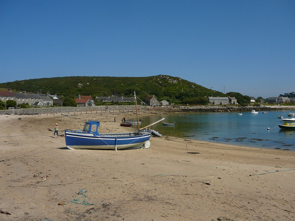 A boat on the sandy beach at New Grimsby on Tresco with the harbour beyond