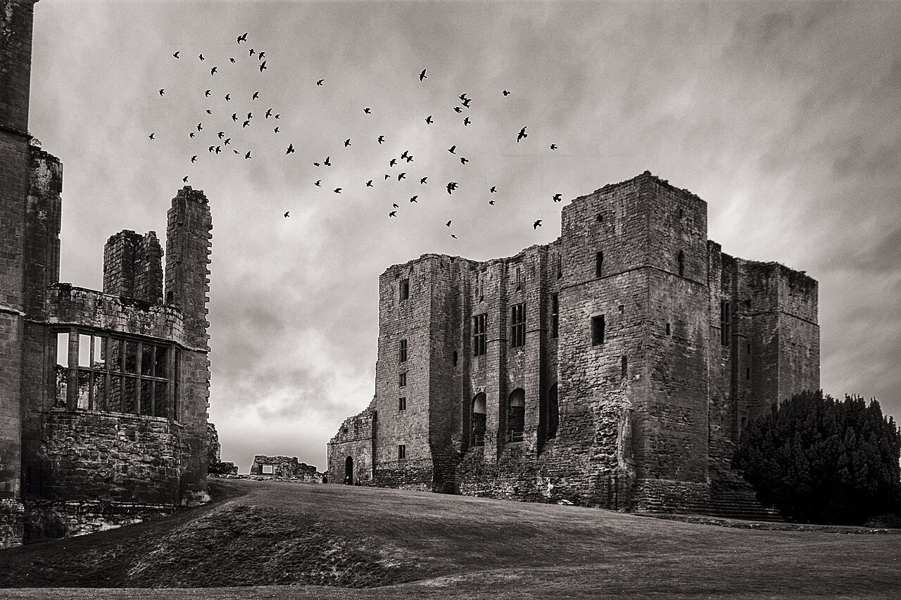 Stone keep and ruined walls at Kenilworth Castle beneath a cloudy sky