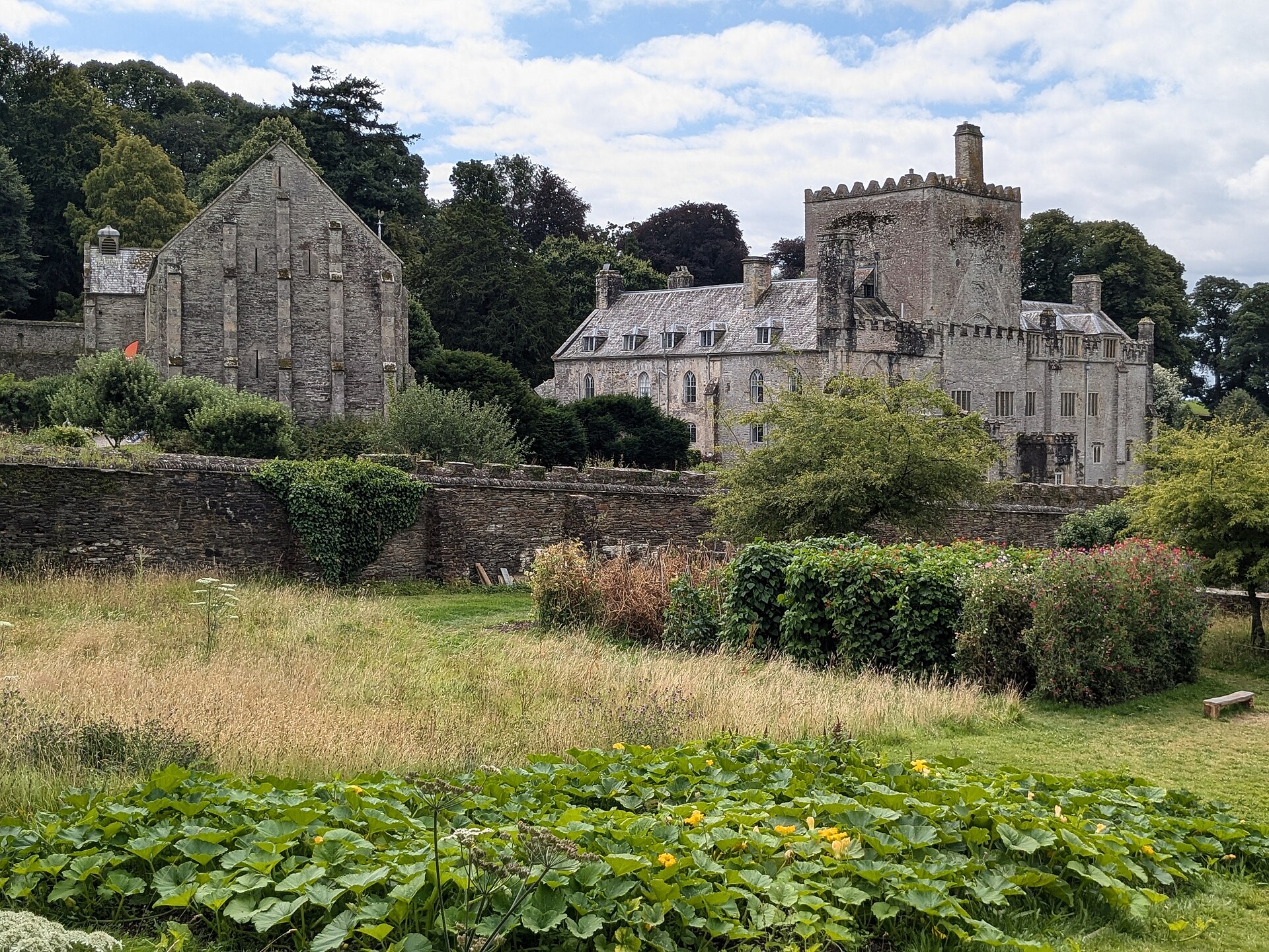 Stone buildings of Buckland Abbey and medieval Great Barn across garden and lawn
