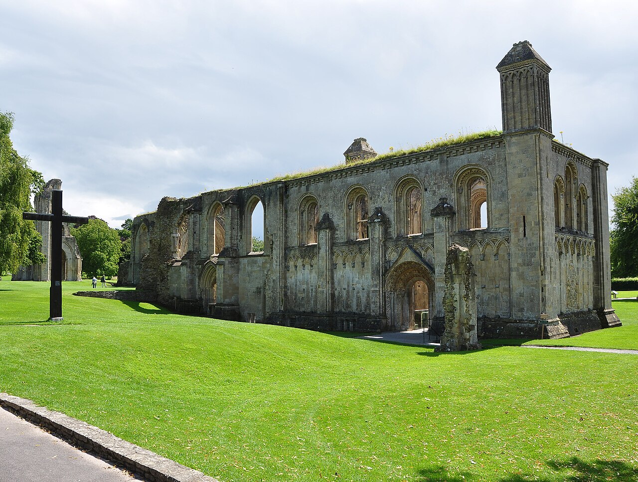 The ruined walls and arches of Glastonbury Abbey above green lawns