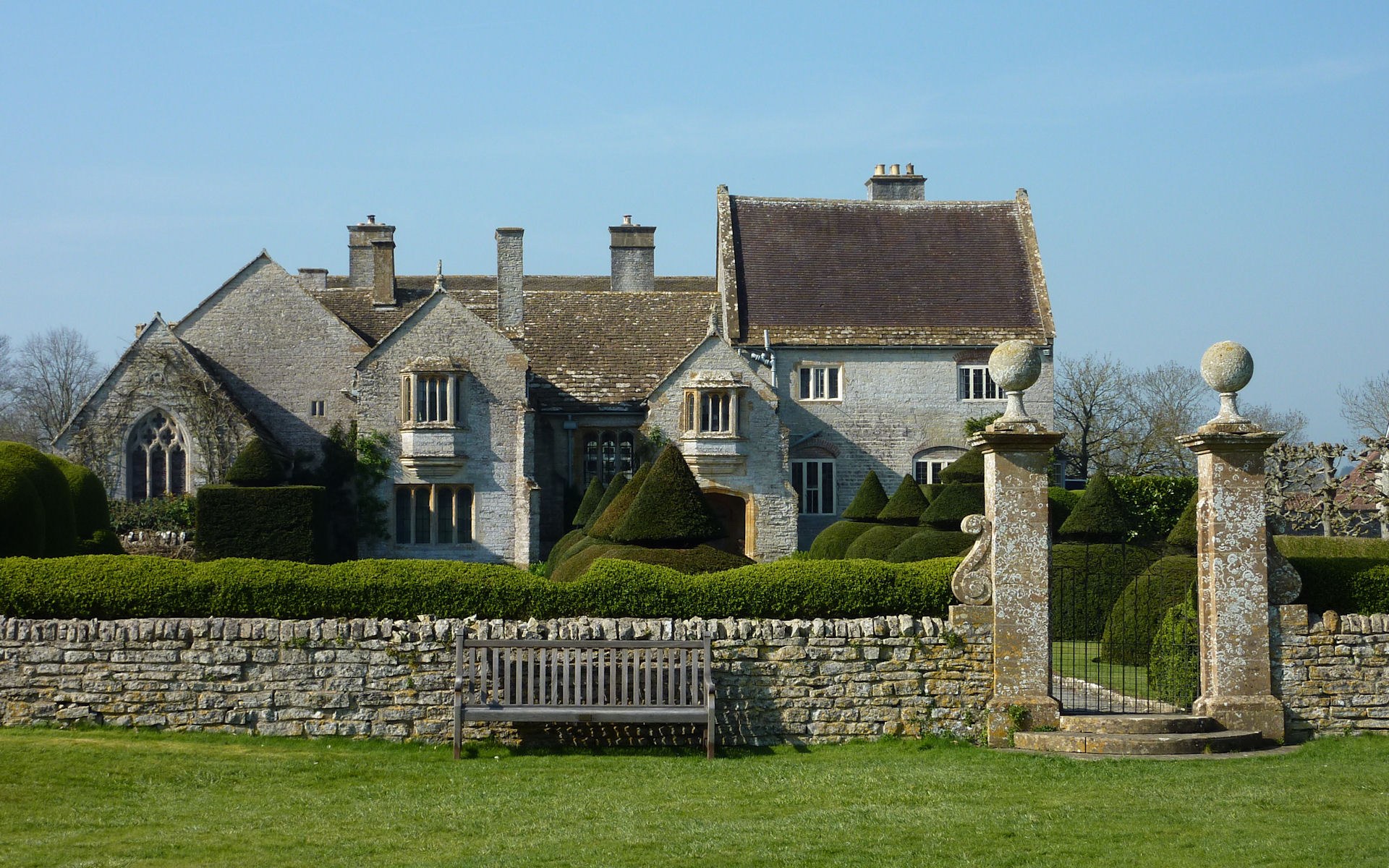 Medieval Lytes Cary Manor behind clipped garden hedges and stone gateposts