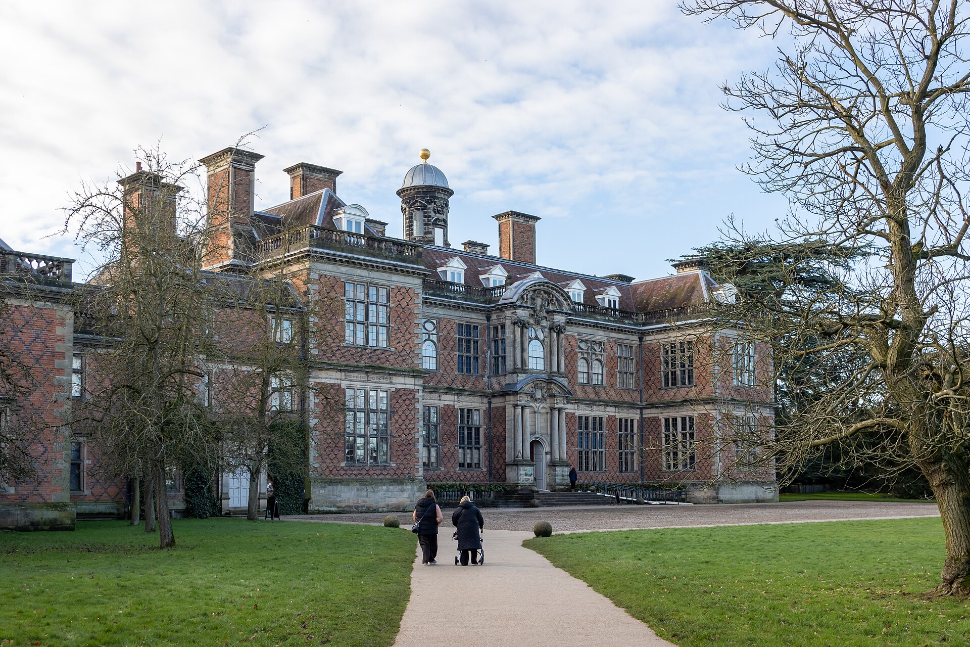 Brick front of Sudbury Hall with a family approaching the entrance