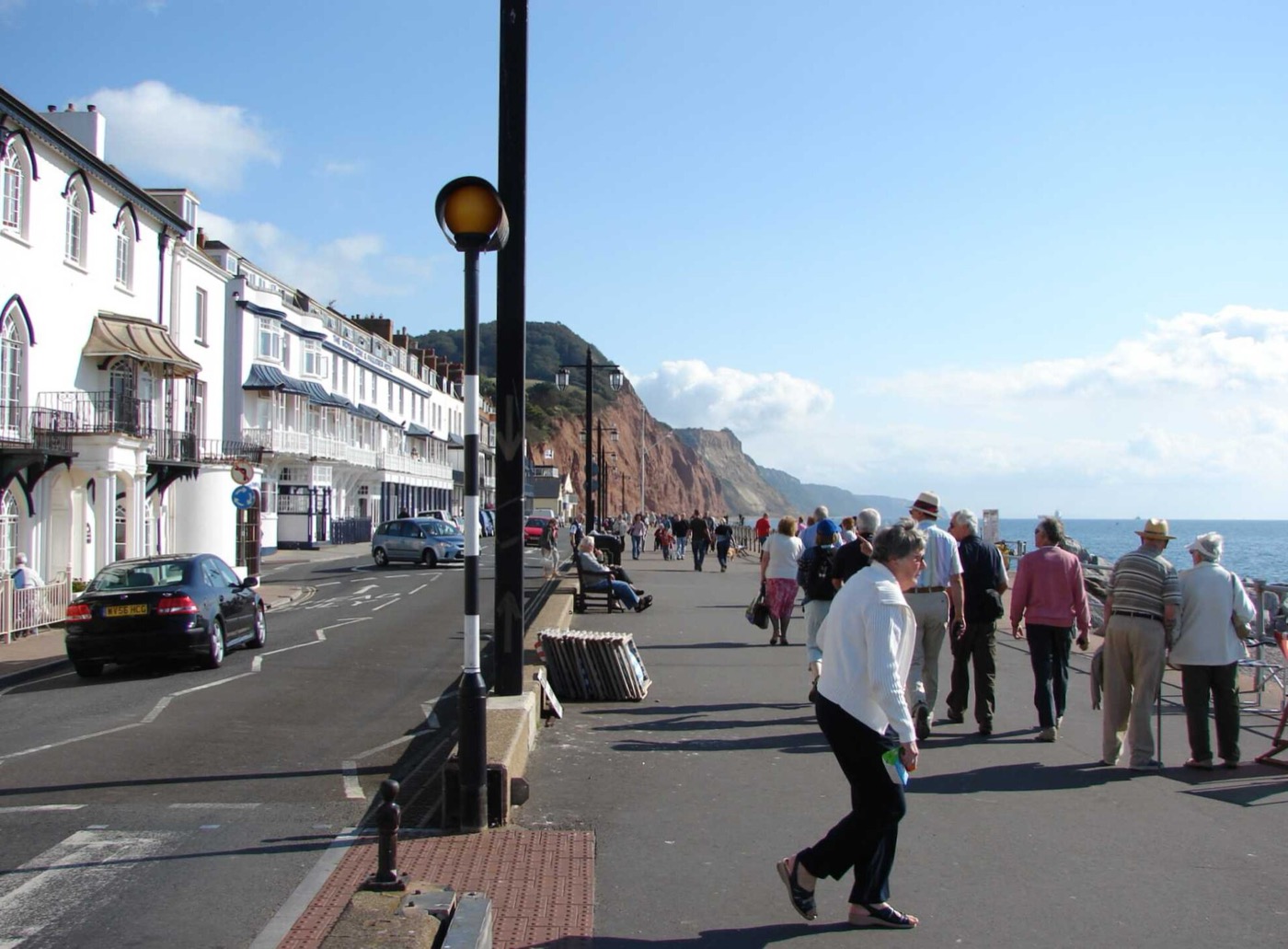 People walking on Sidmouth Esplanade beside the sea