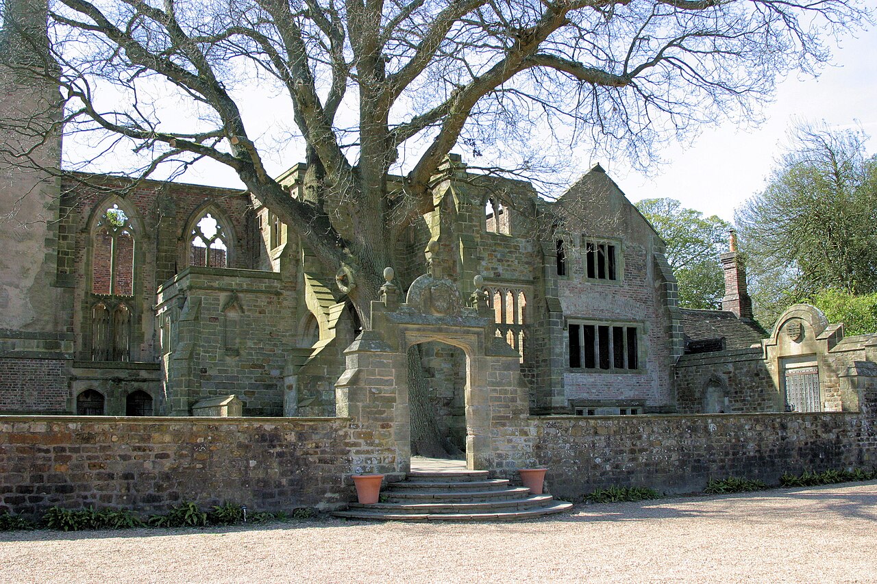 Ruined stone house at Nymans behind a garden wall