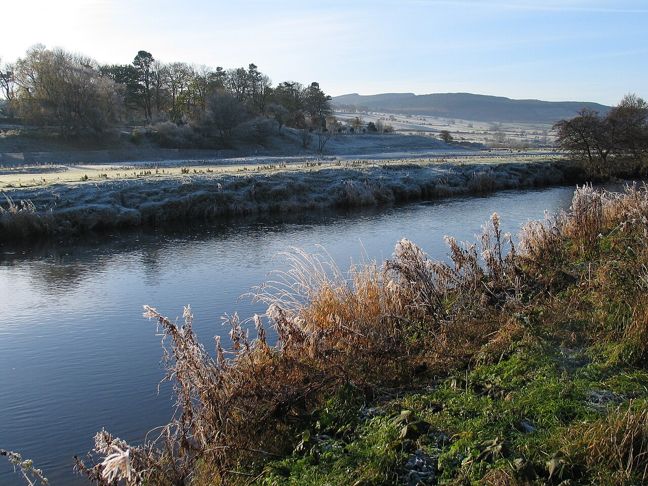 River Coquet beside frosty banks and stone buildings in Rothbury