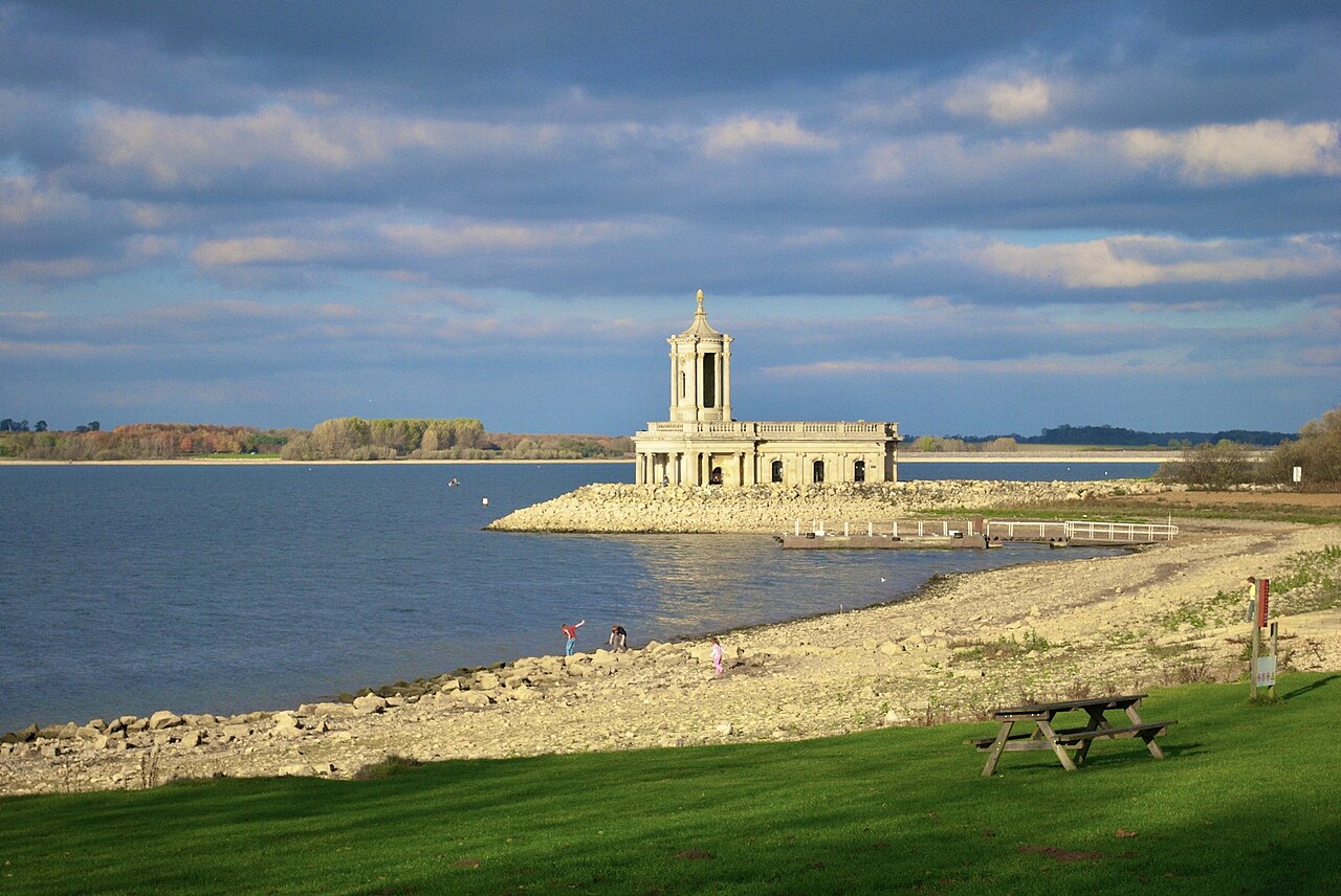 Normanton Church beside Rutland Water with a grassy shore in the foreground