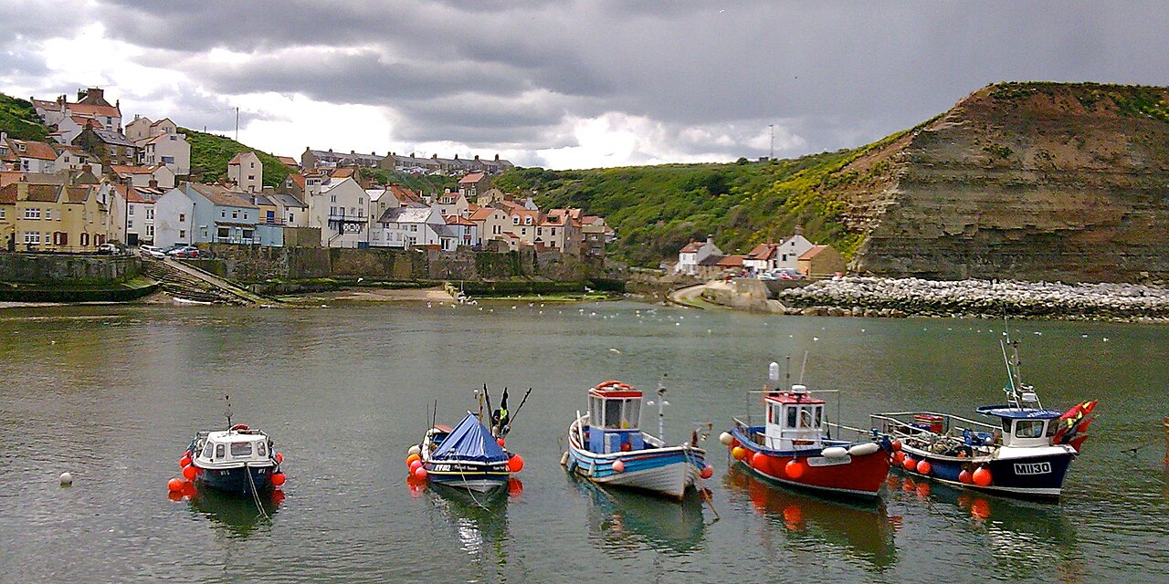 Fishing boats in Staithes harbour beneath cottages and cliffs