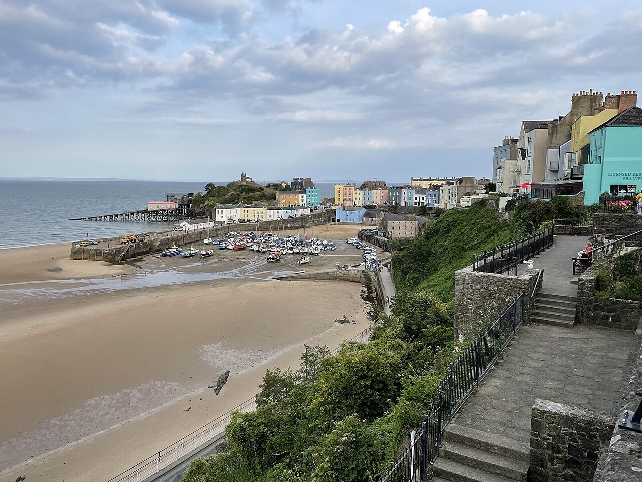 Boats on exposed sand below Tenby’s colourful harbour buildings